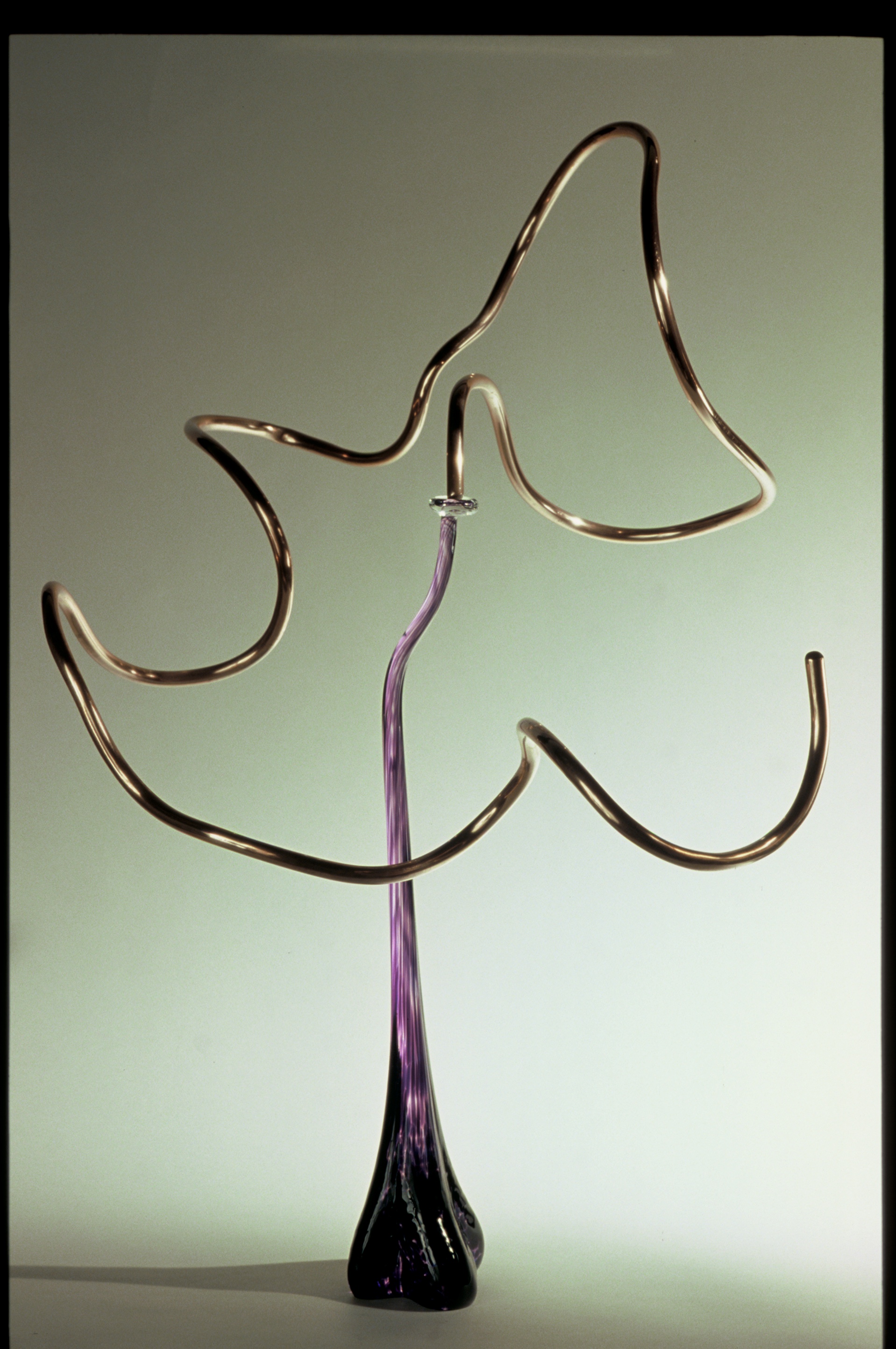 Minimalist metal sculpture with curved shapes against a gradient background.