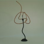 Abstract wire sculpture with intertwined loops on a stand.