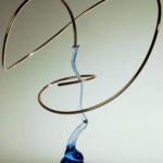 Abstract sculpture with spiraling metal and blue glass elements.