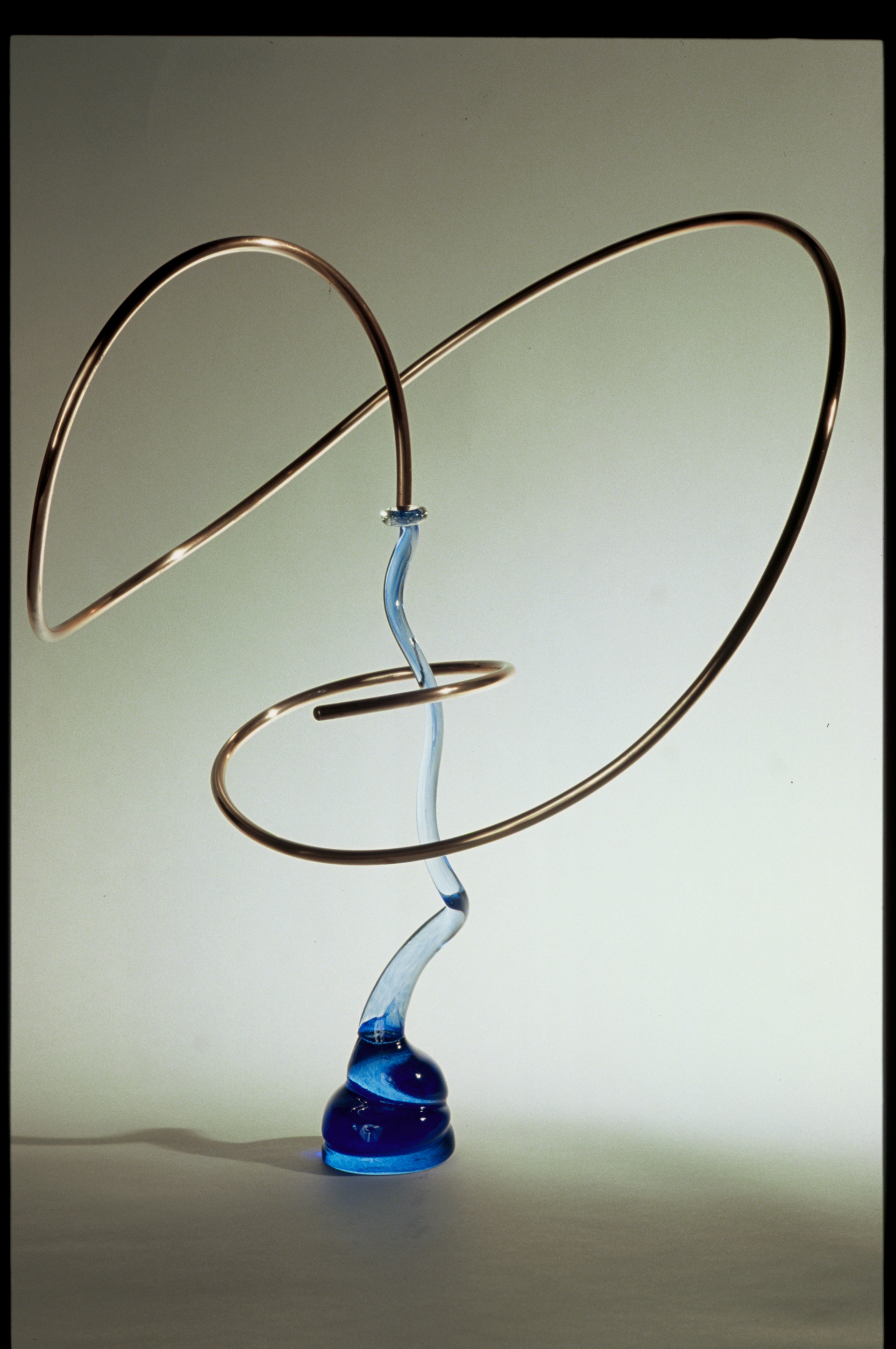 Abstract sculpture with spirals and blue accents against a neutral background.