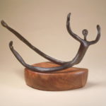 Abstract bronze sculpture of a reclining figure on a wooden base.