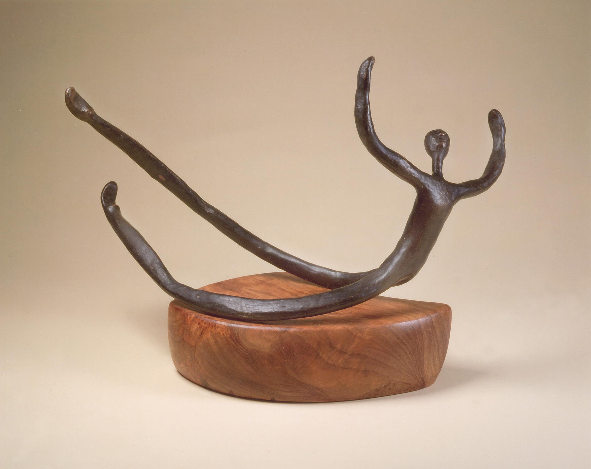 Abstract bronze sculpture of a reclining figure on a wooden base.